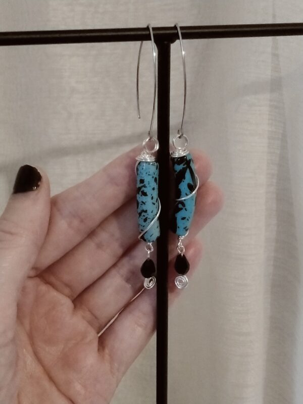 Paire de boucles d'oreilles avec leurs perles incurvées noires et bleues et la perle de verre
